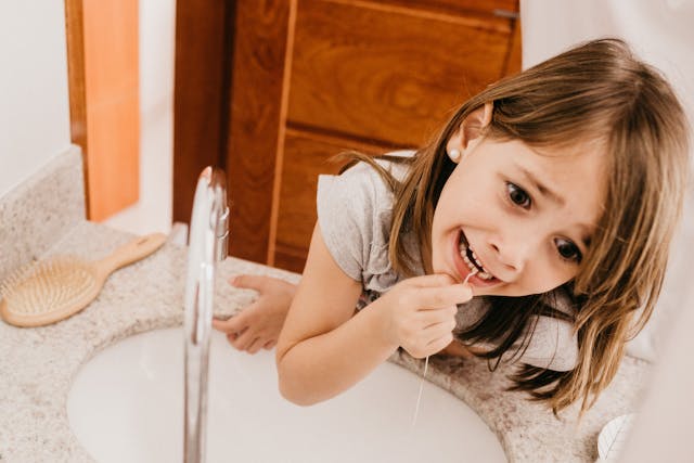 pediatric flossing child flossing her teeth